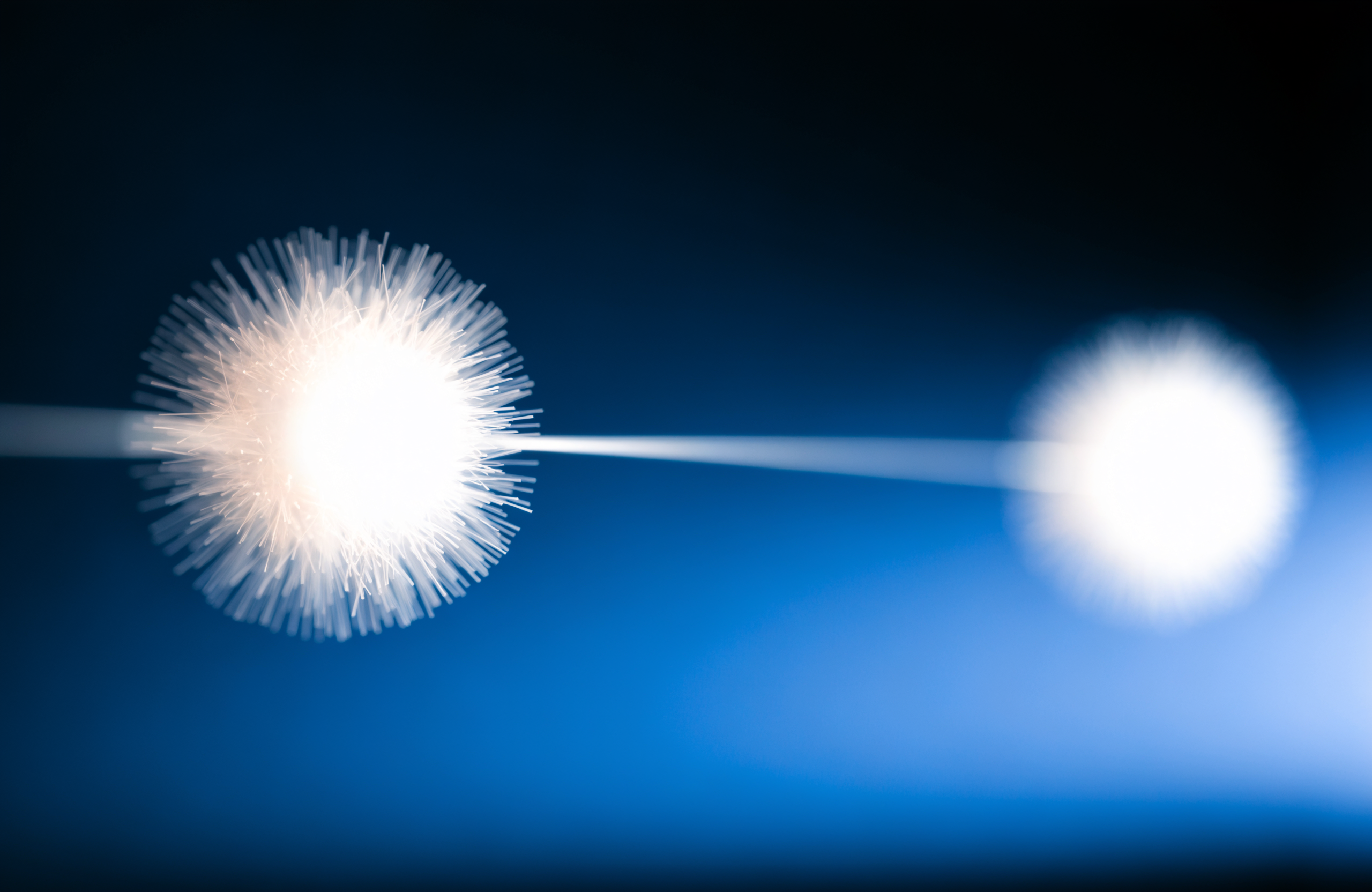 Two glowing digital nodes of light connecting across a dark navy and blue background, representing AI agents communicating on behalf of businesses and customers
