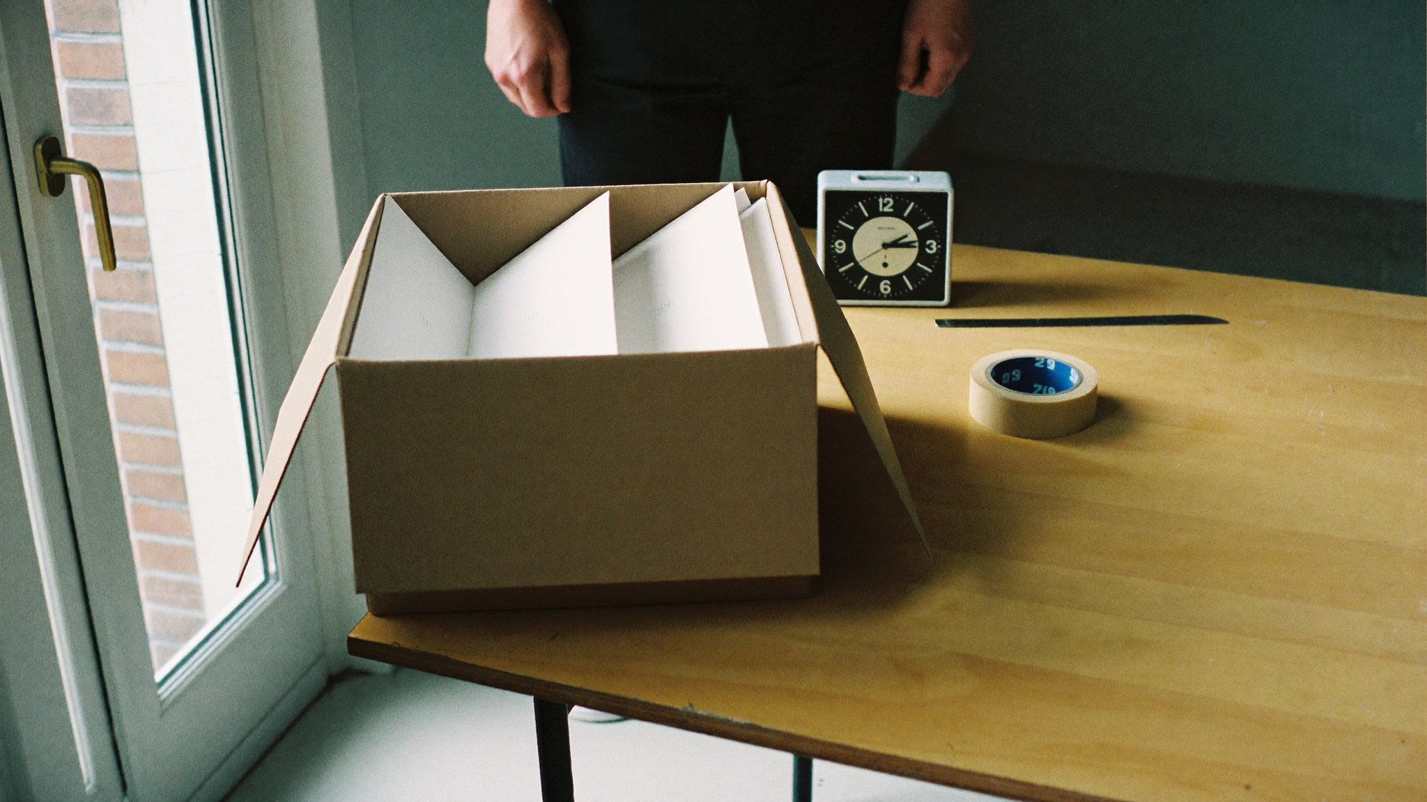 A studio table with printed sheets and a clock turned face down