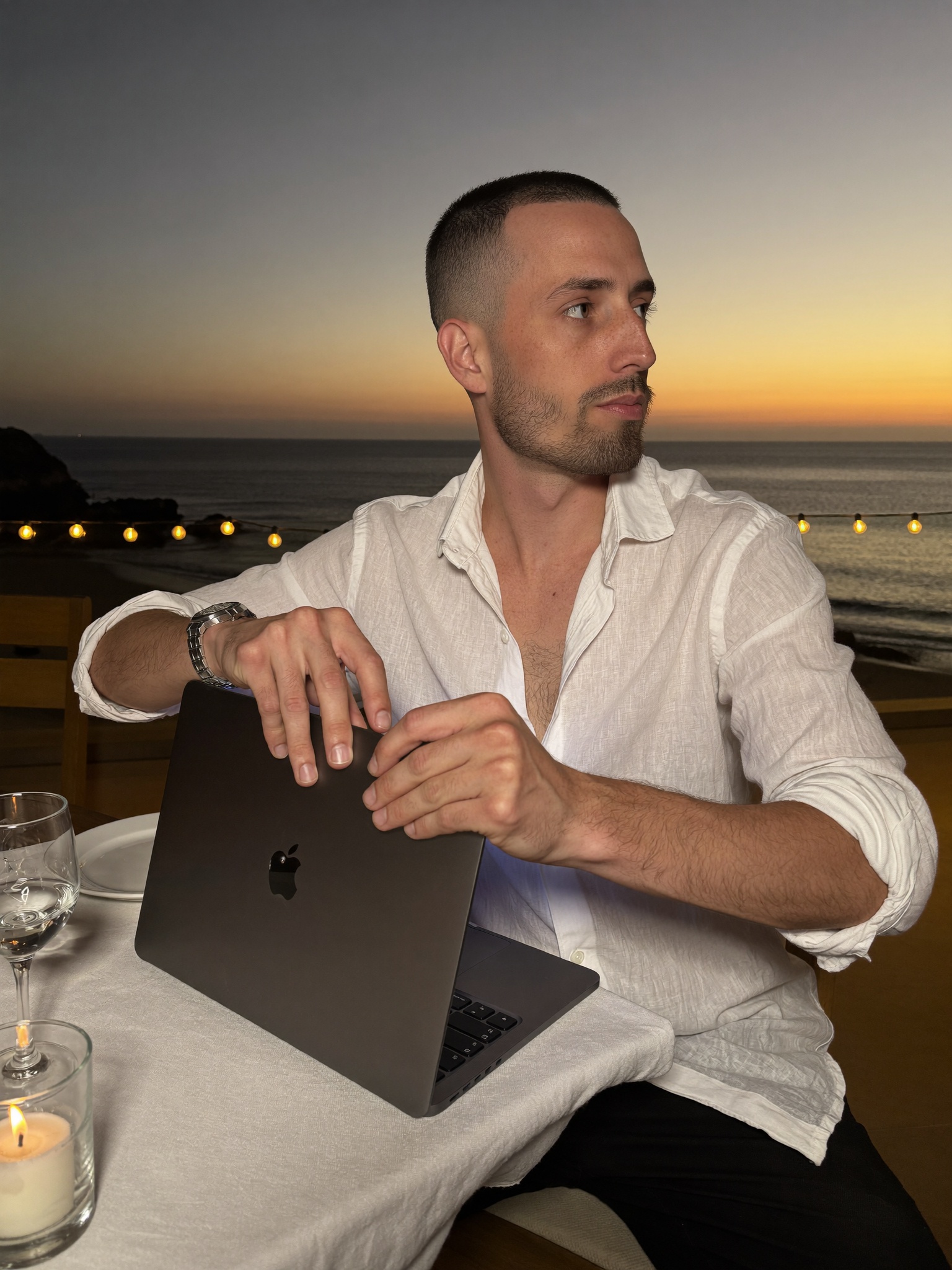 Cody Wise closing a laptop at a beachfront table at dusk