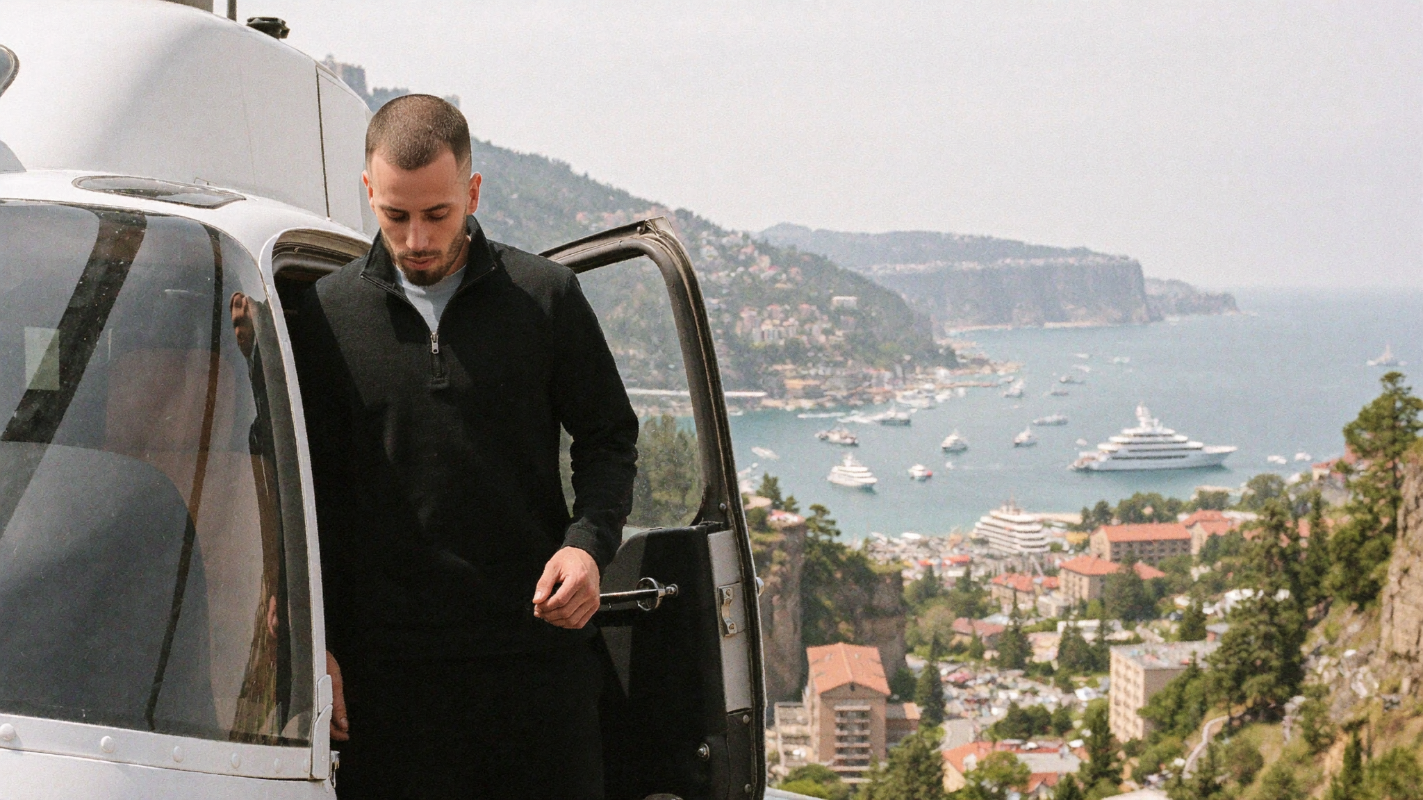 Founder stepping down from a helicopter on a coastal helipad above Monaco