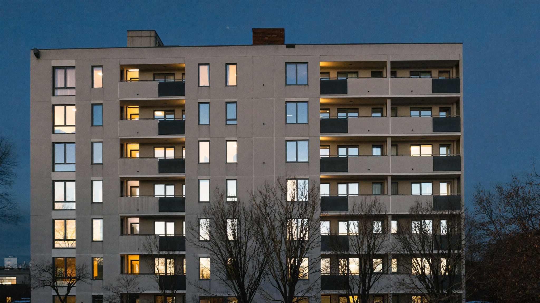 A mid-rise apartment building at dusk, the physical asset that sits underneath any property token