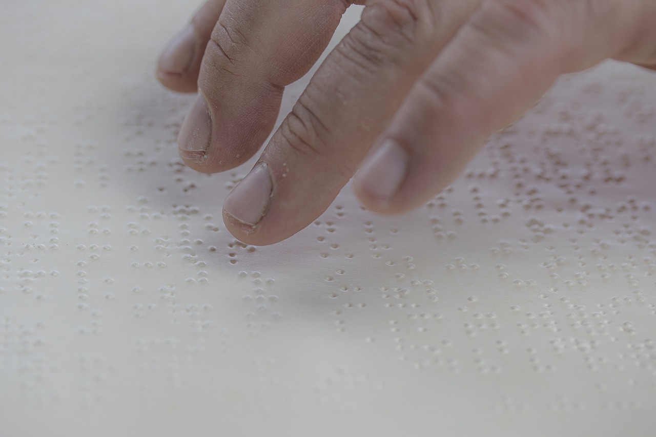 A person reading a line of braille text with their fingertips