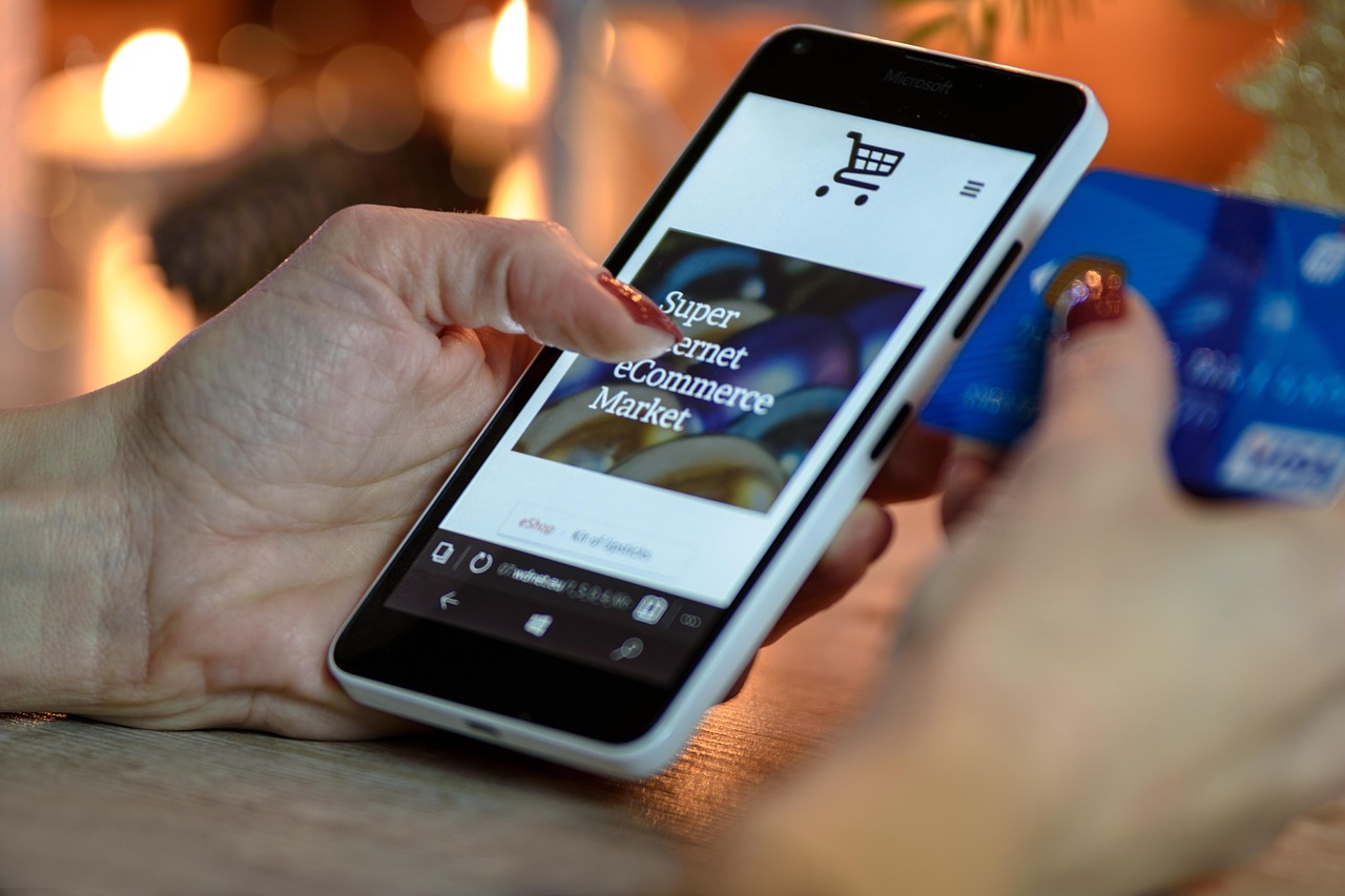 A hand on a phone mid purchase decision, the conversational moment ChatGPT ads are designed to sit beside.