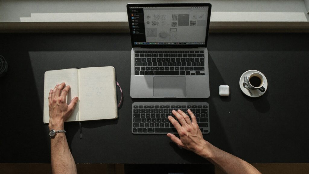 Overhead view of a laptop and notebook on a desk, representing the intake and booking workflow behind a clinic website