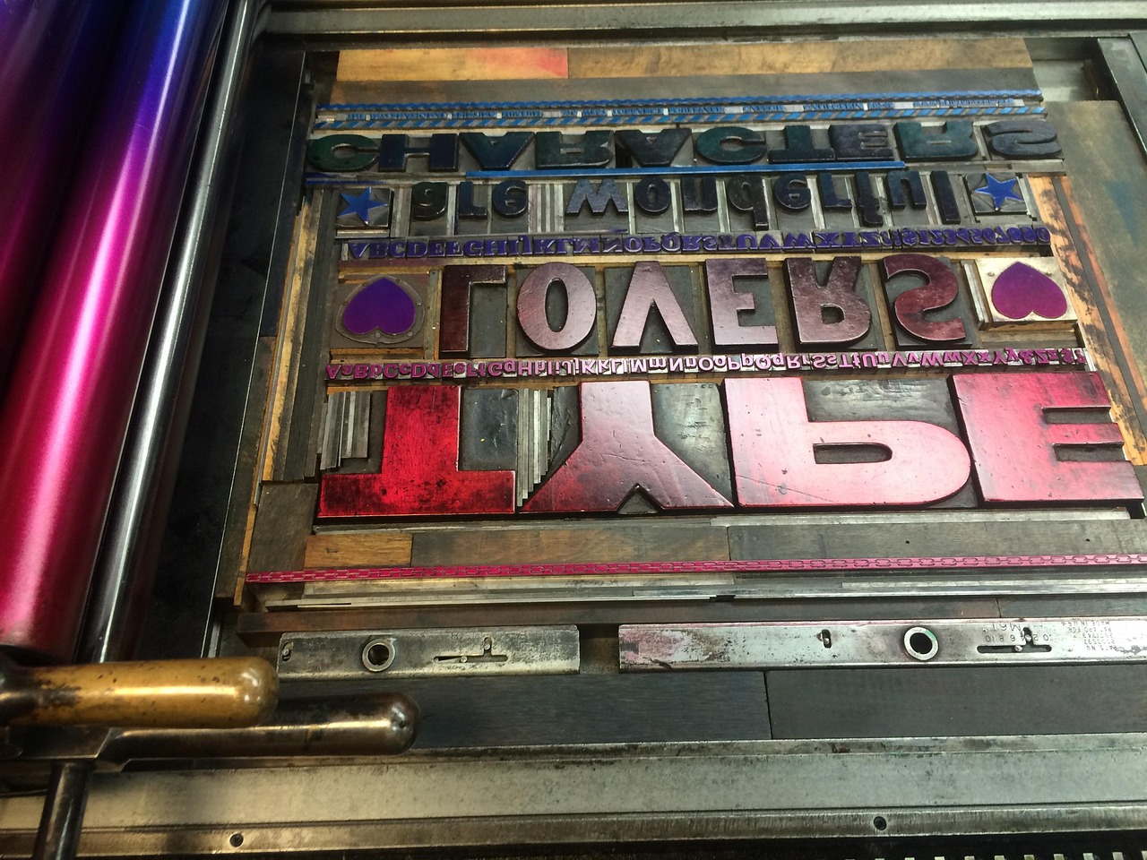 Inked metal letterpress type in a press bed, representing the typography system inside a brand identity package.