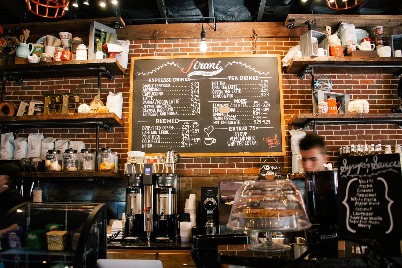 Staff working behind a cafe counter under a chalkboard menu, the exact point of contact where most on-premises review requests are made.