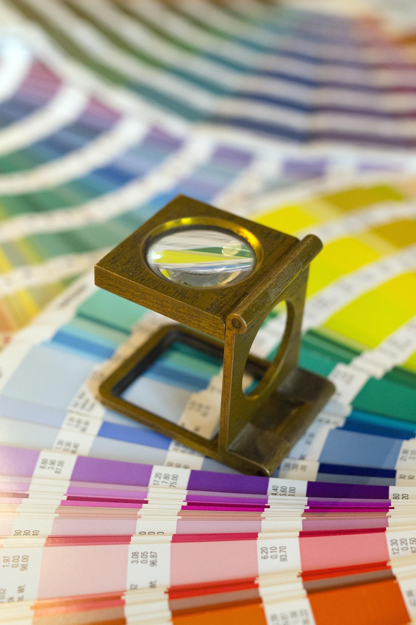 A printer loupe resting on a colour proof strip, the production check that exposes whether a brand palette was specified in CMYK and Pantone.