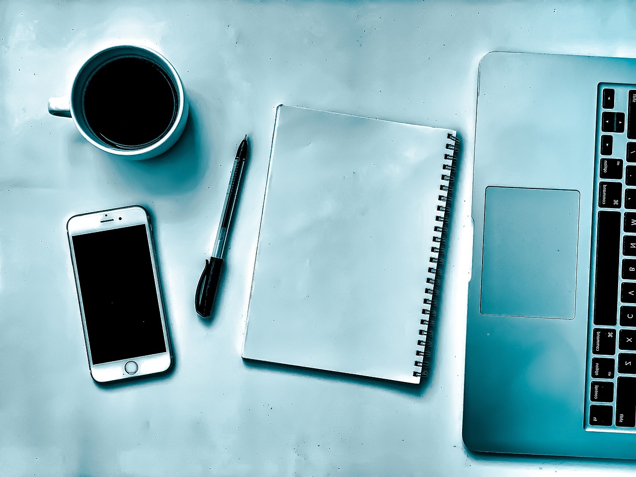 Flat lay of a laptop, notebook, pen and phone on a desk, representing the script and data inventory behind a Canadian website privacy policy