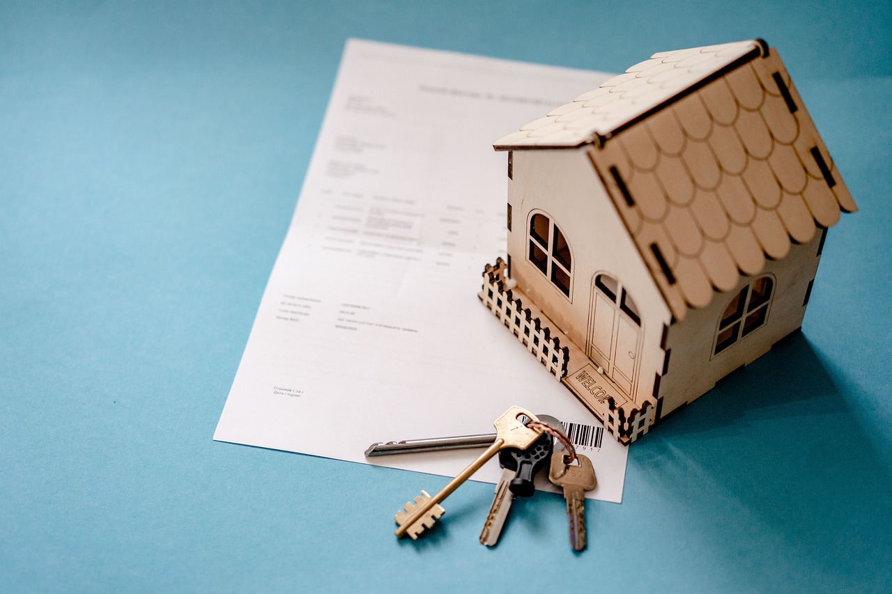 Property documents beside a small model house, illustrating the paperwork behind realtor website listing compliance.