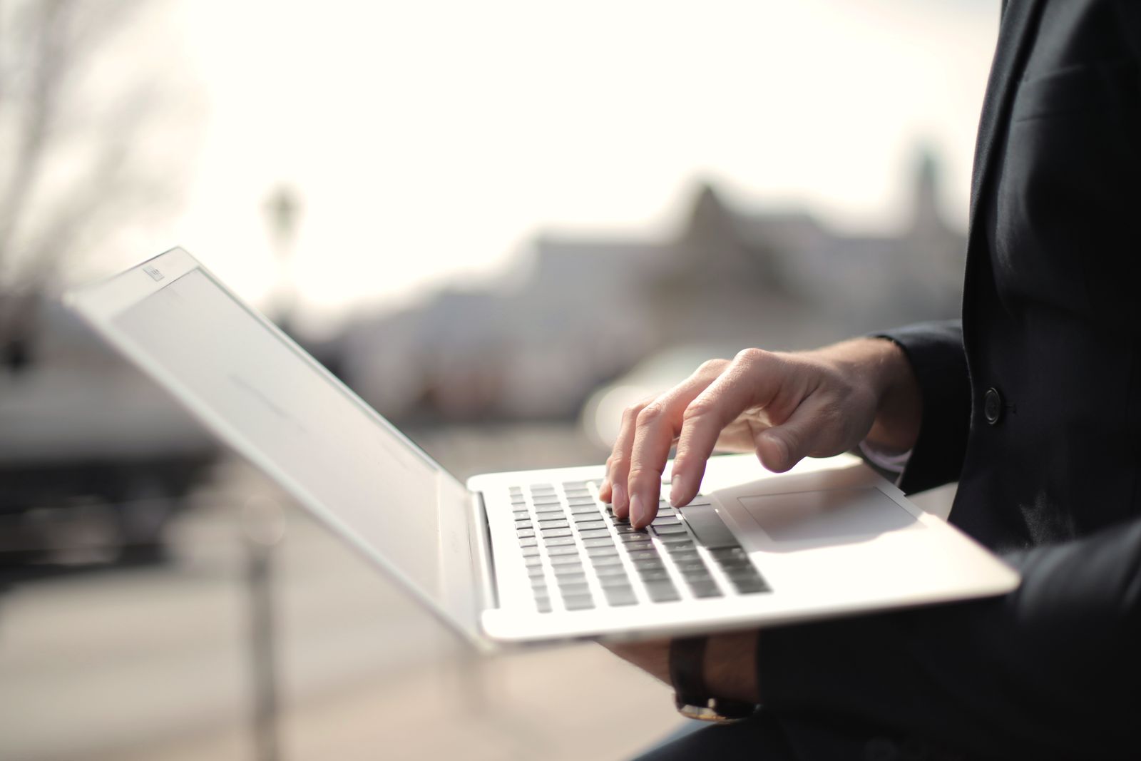 A hand on a laptop keyboard in window light, making a single change to a campaign bid target