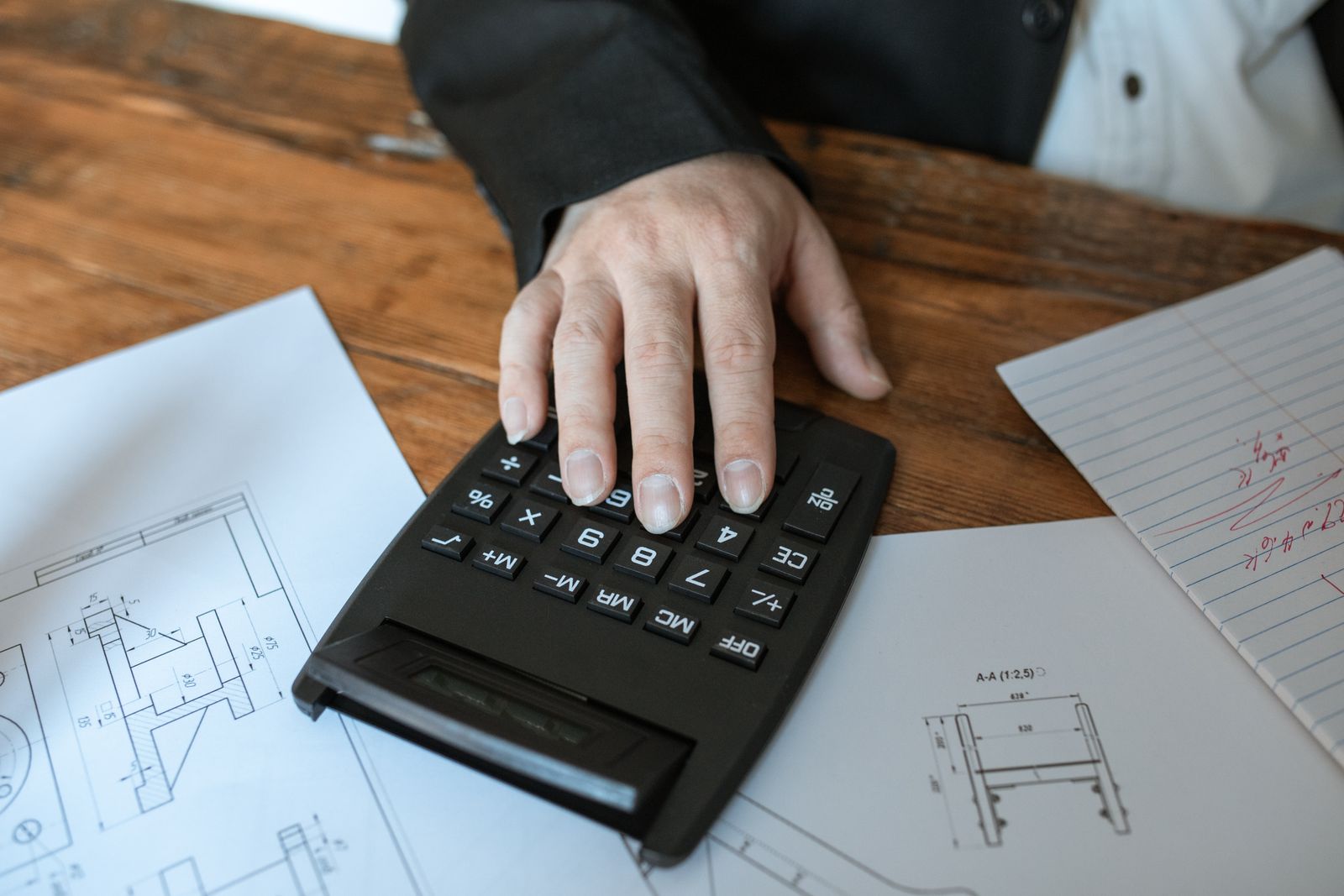 Hands using a calculator beside printed paperwork to total the real annual cost of short-term rental management