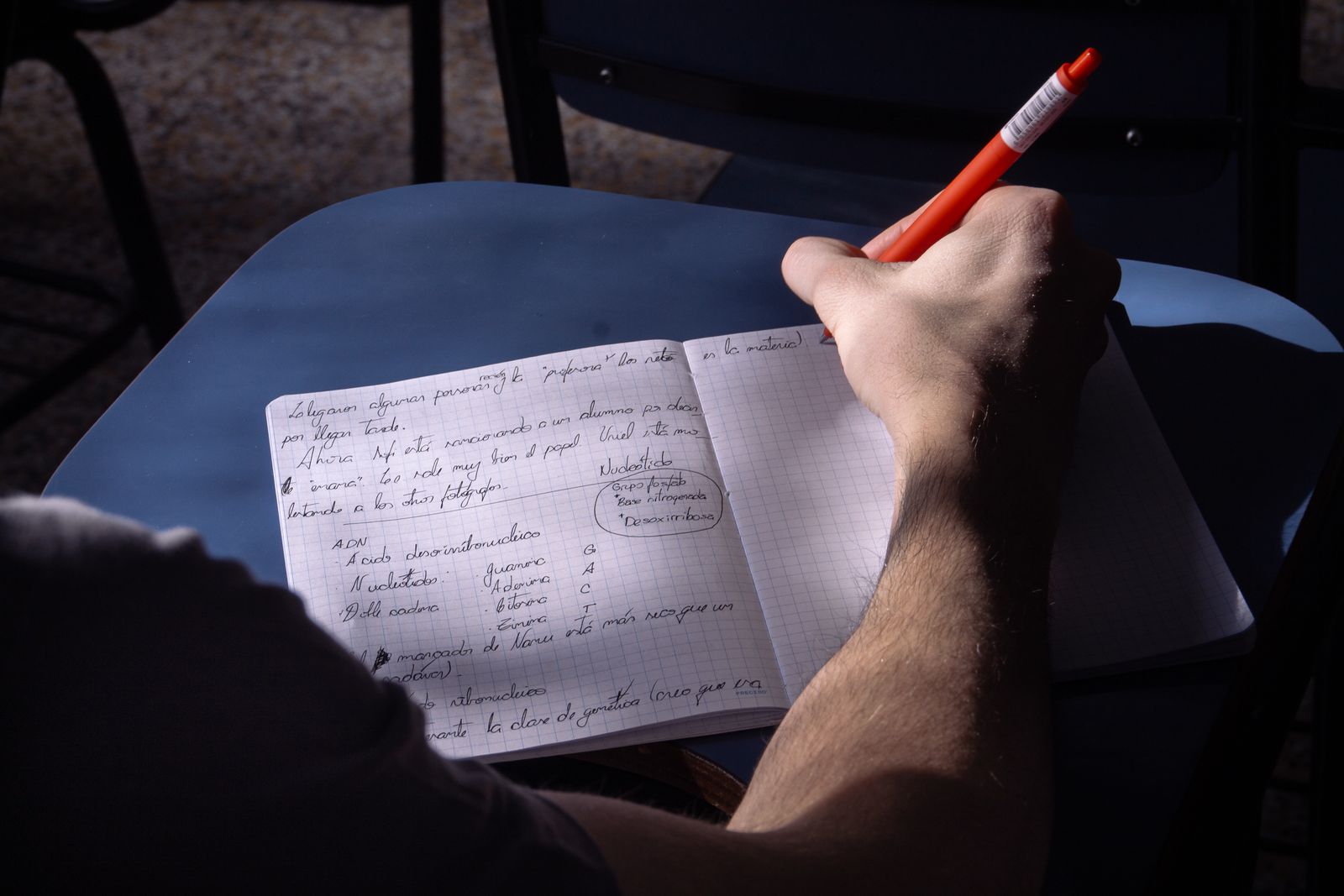 A hand writing notes in a notebook at a dark desk, working through a Google Ads diagnostic step by step