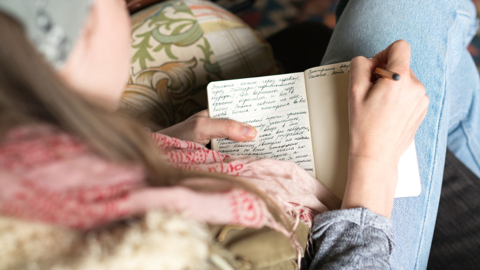 A hand writing a list of questions in a notebook before signing a short-term rental management agreement