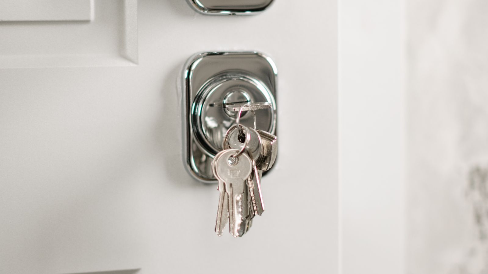 A set of keys left in a door lock, representing the question of whose name holds the short-term rental business licence